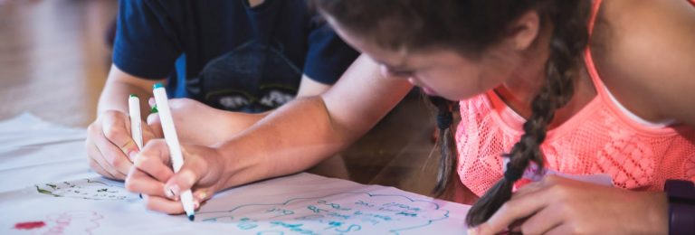 Two kids writing messages on a piece of paper
